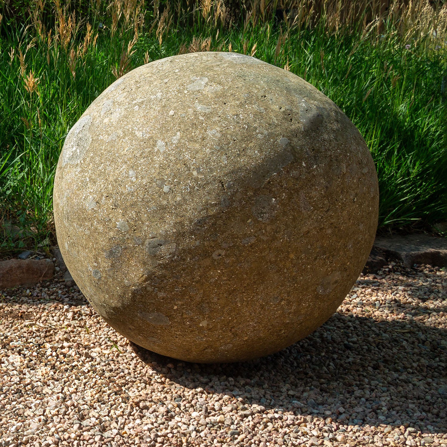 39" Large stone sphere on a gravel surface with grass in the background
