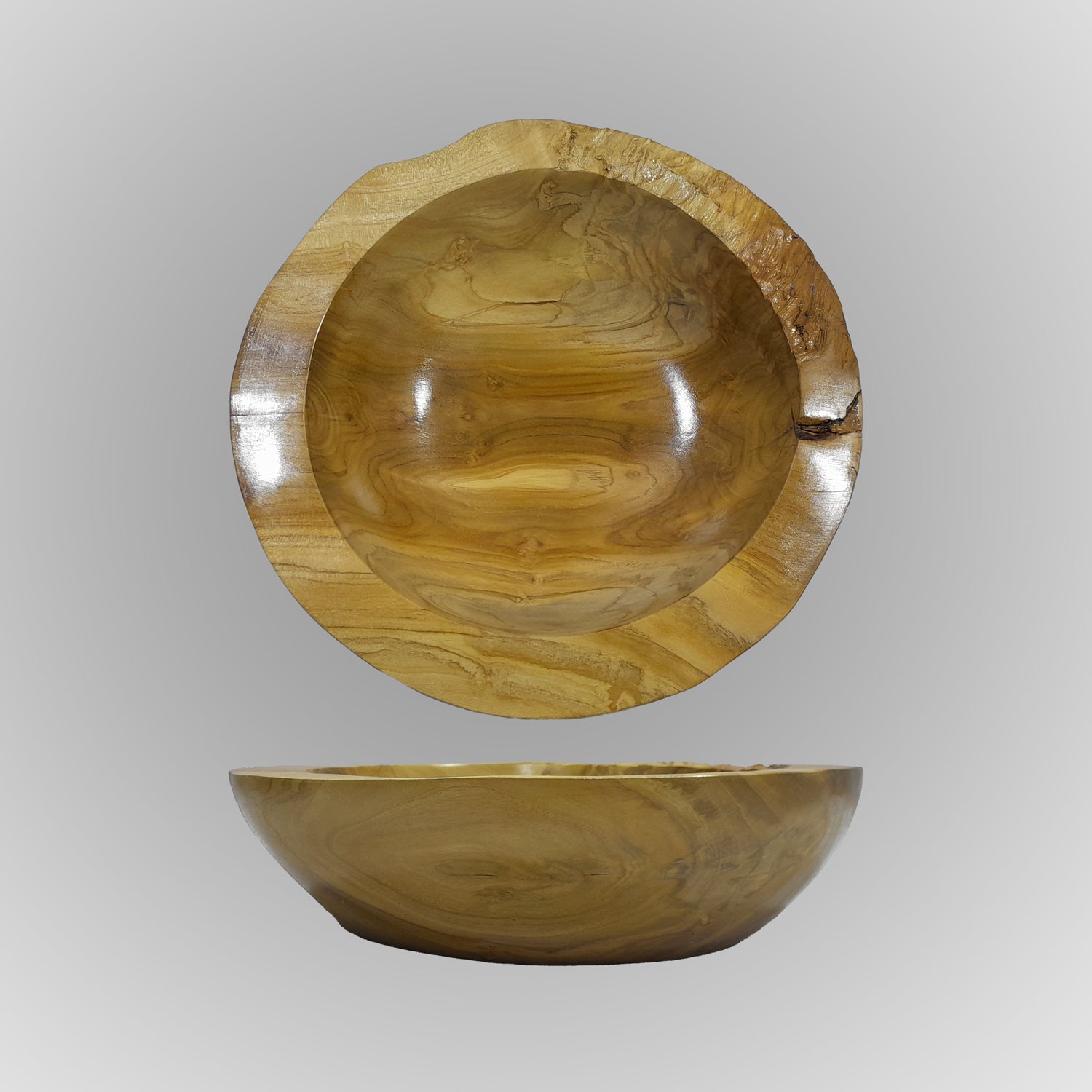 A hand-carved teak wood bowl with a smooth finish, showing natural wood grain, is displayed on a gray background