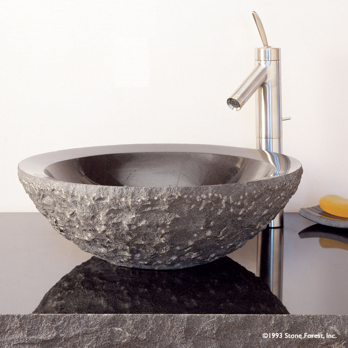 Beveled Rim vessel sink carved from black granite with rough chiseled exterior and polished interior. image 1 of 1