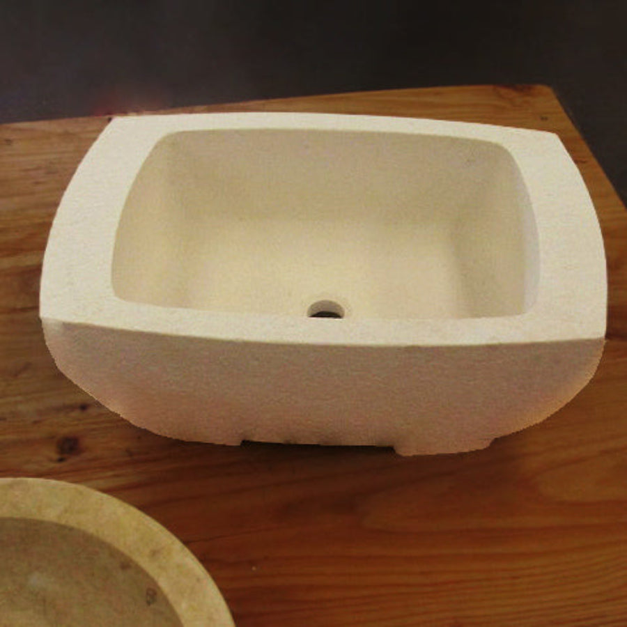 A beige, rectangular vessel sink made of Papiro cream marble, placed on a wooden surface.