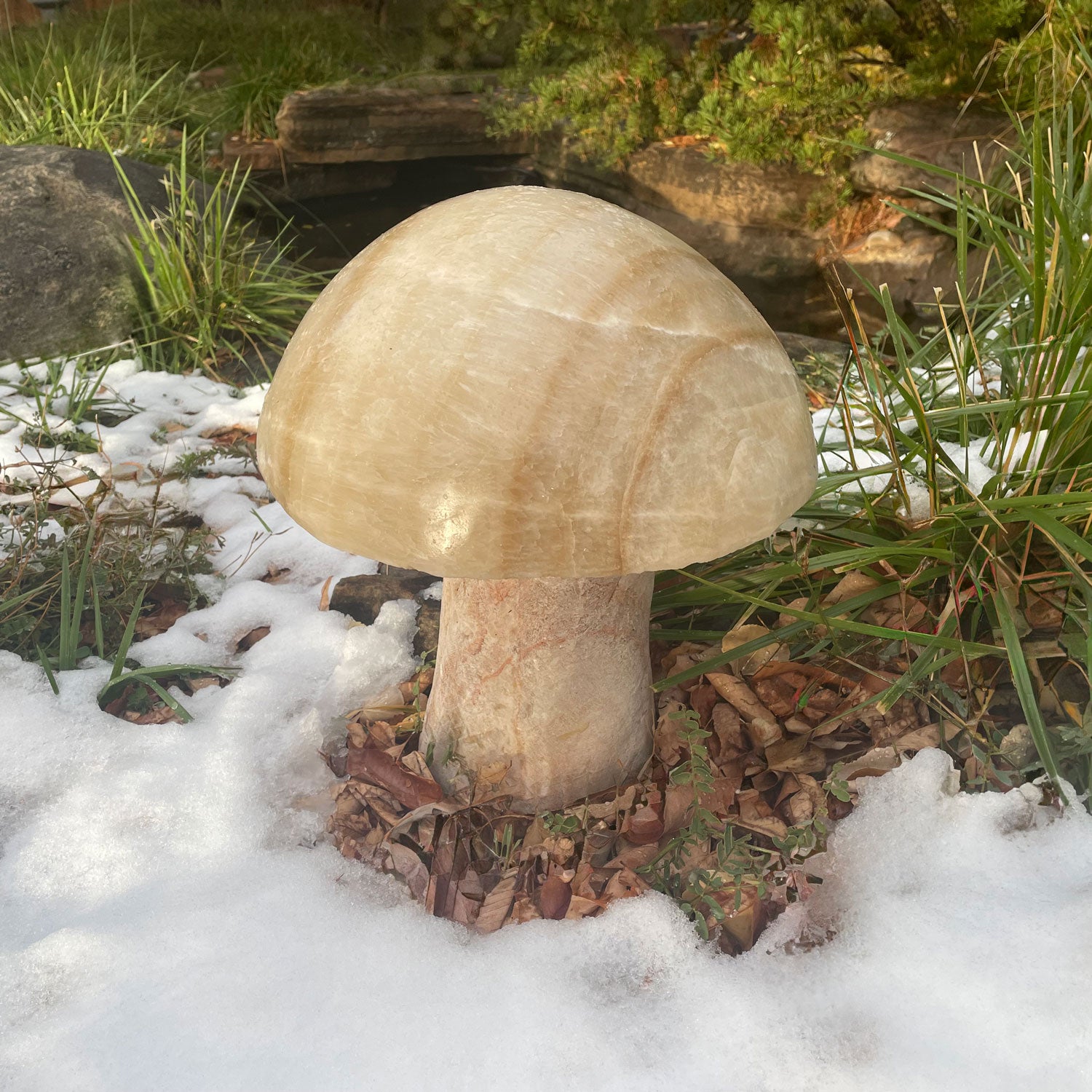 A garden mushroom carved from onyx, placed in a garden setting.