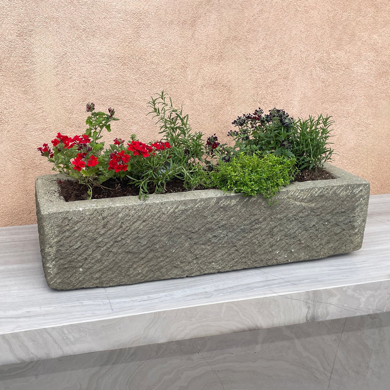 Decorative stone planter with plants on a neutral background