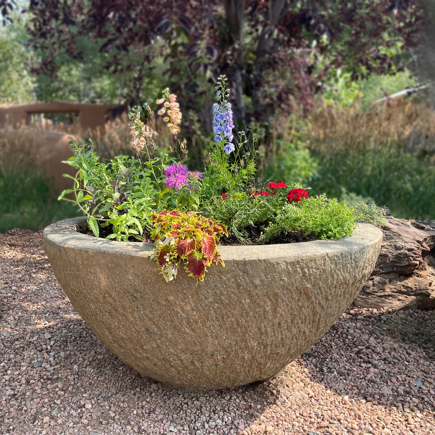 Decorative stone planter with colorful flowers in a garden setting