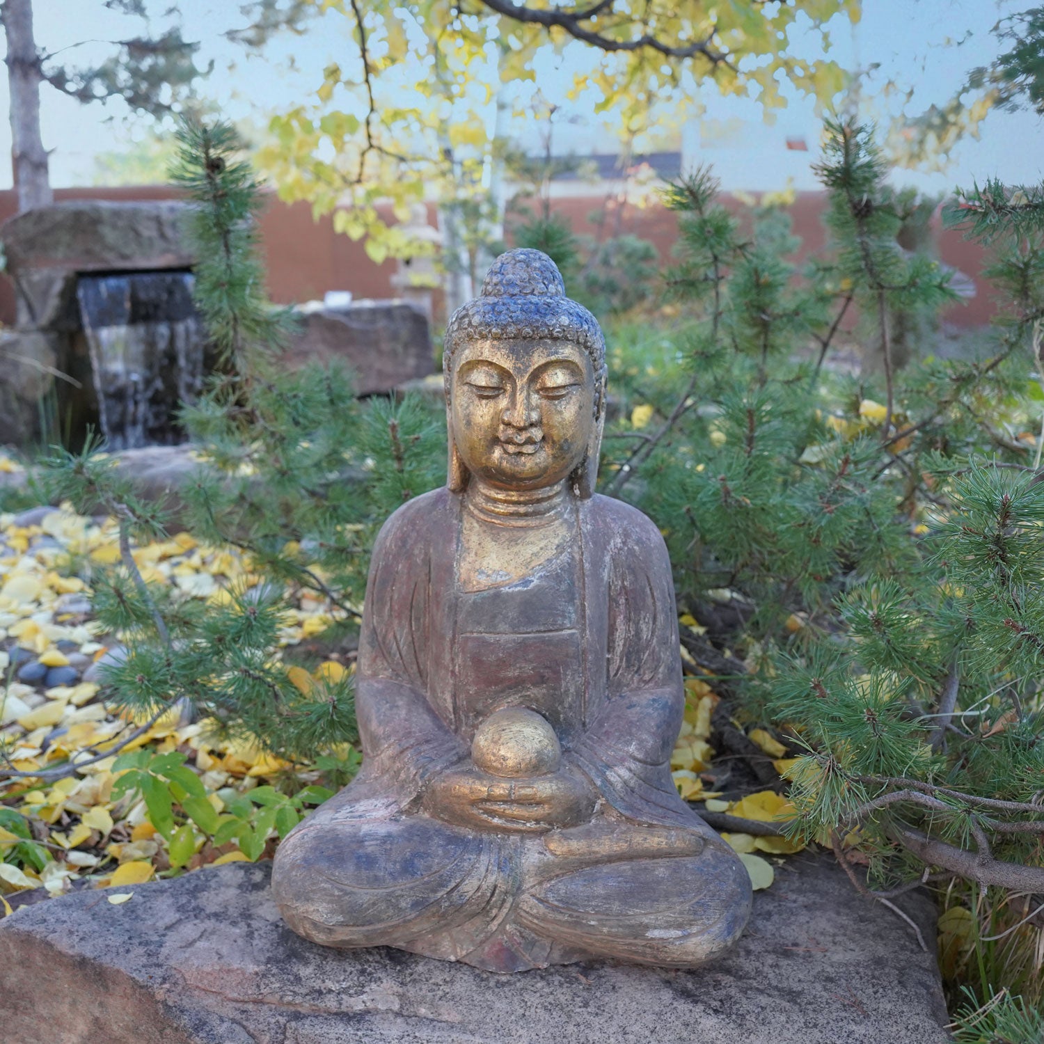 A hand-carved dark limestone Buddha statue with a painted finish, seated