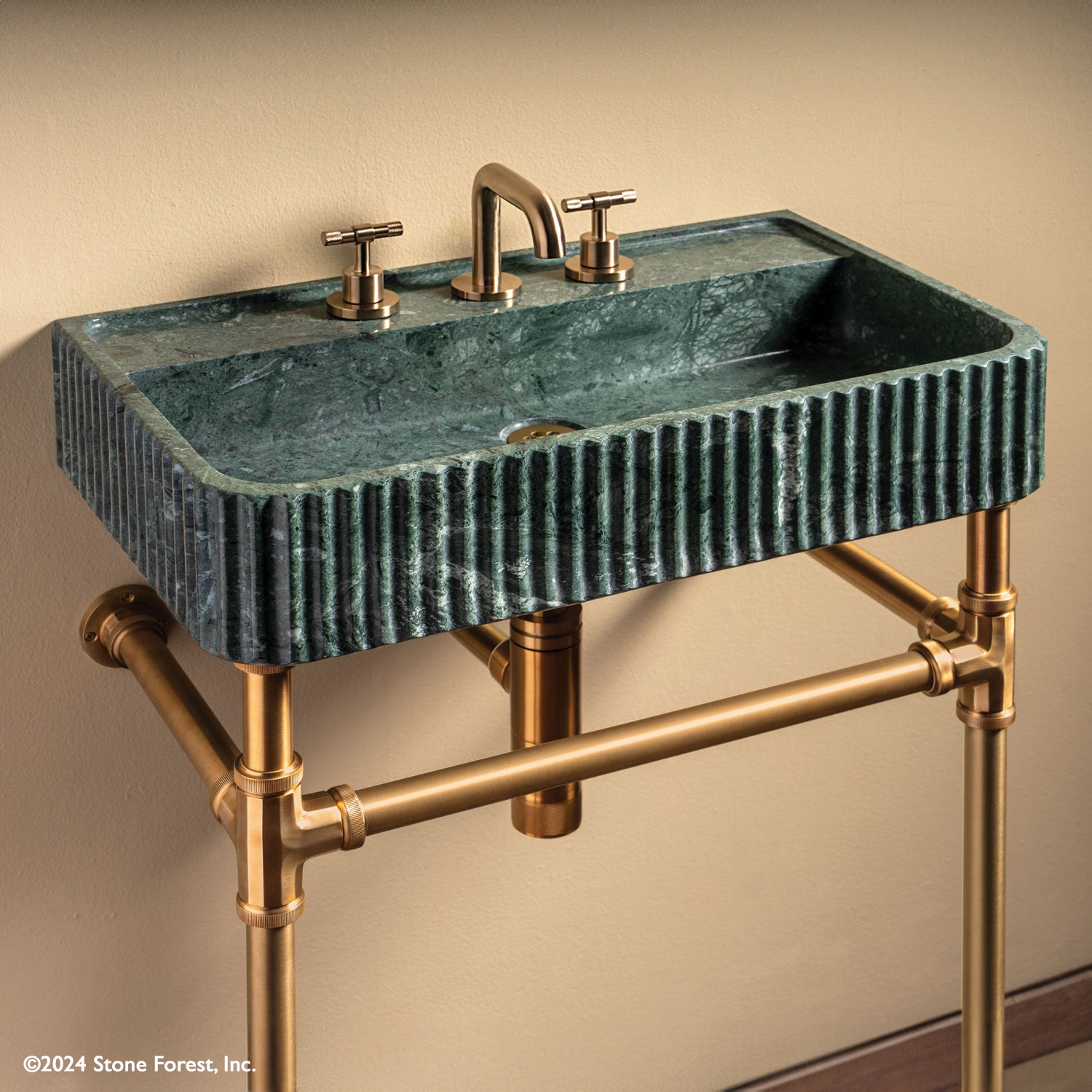 Fluted Lumbre Bath Sink carved from Verde Indio Marble on top of an Aged Brass Elemental Facet Crossbar Stand