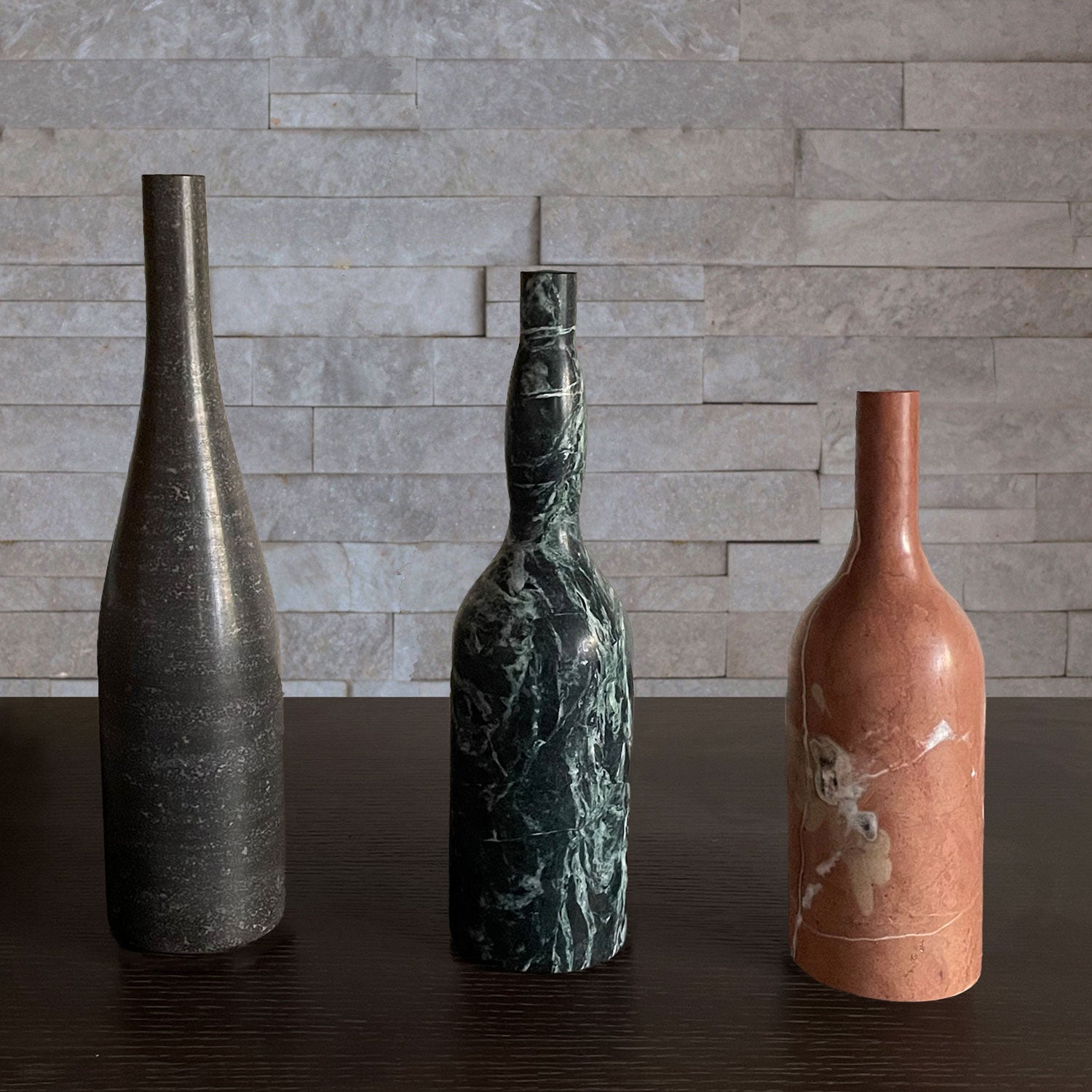 Three marble bottle forms are hand-carved from different types of stone.