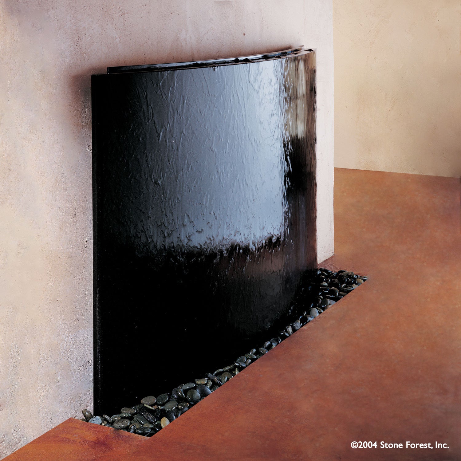 A polished black granite, slightly curved granite waterwall fountain with water sheets over the face.