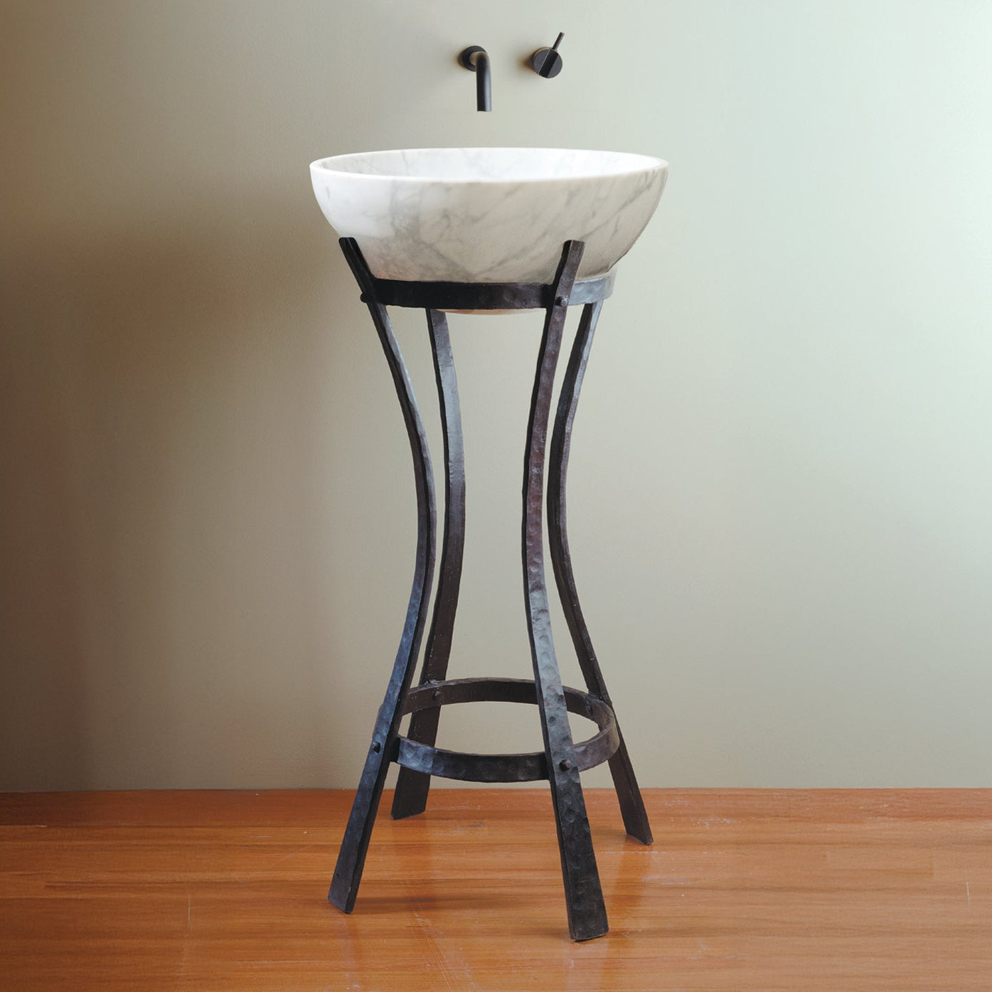 Carrara Marble sink on an Iron Pedestal against a plain wall.