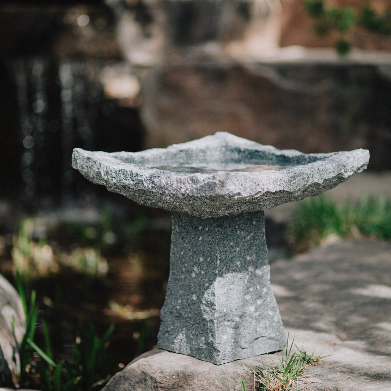 This birdbath is hand-carved from blue-gray granite with a rough chiseled finish