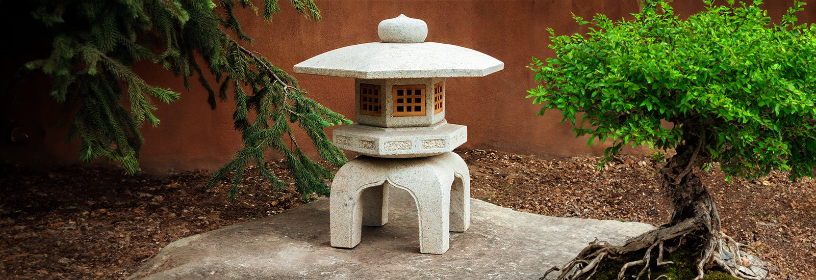 Antique Yukimi Lantern in beige granite on rock with trees