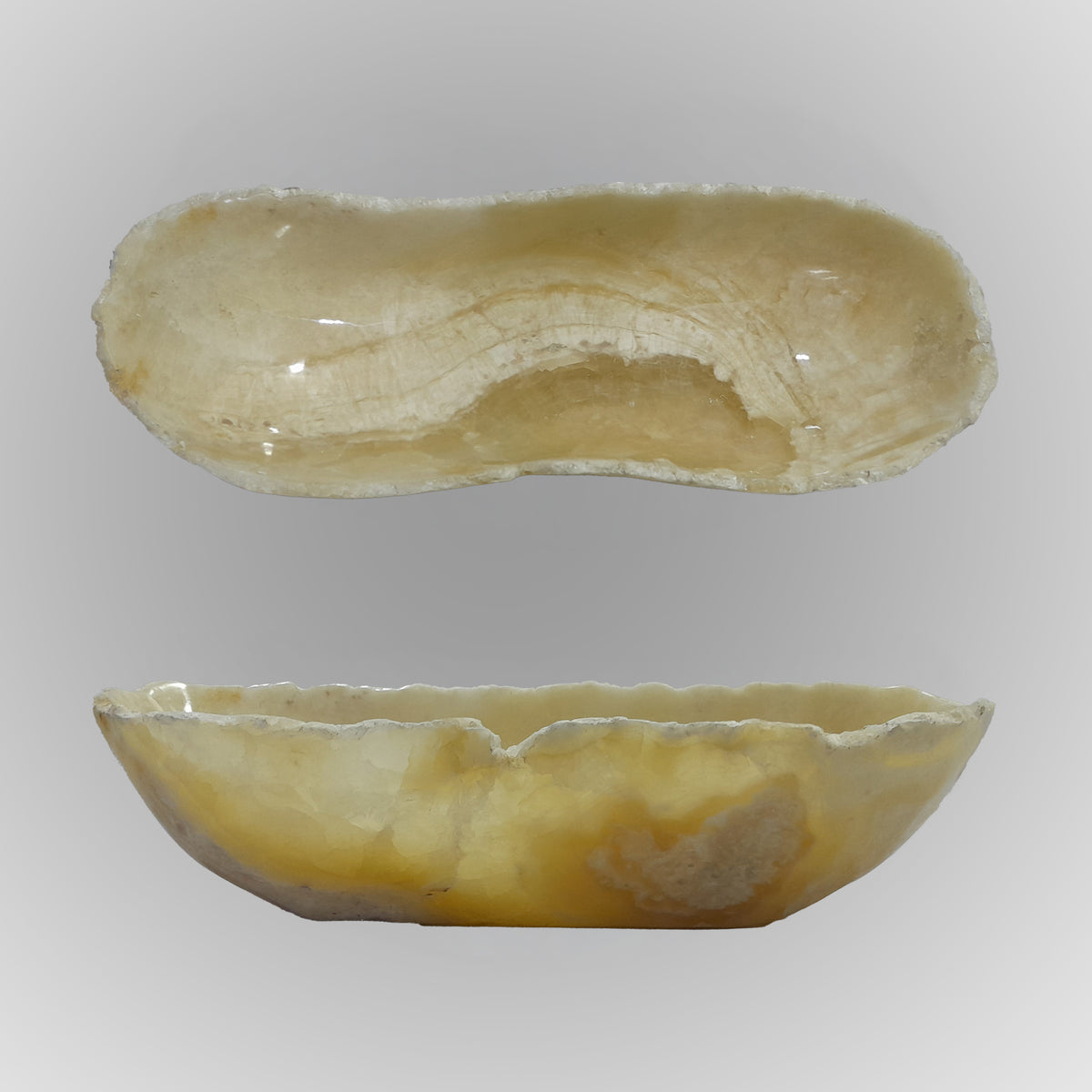 A free-form onyx bowl with a smooth, curved shape, honey and beige coloring
