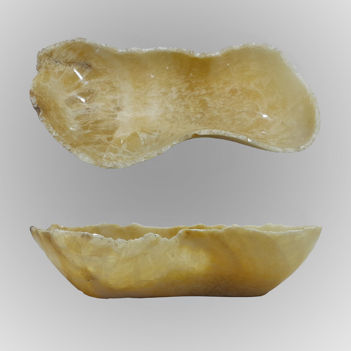 A free-form onyx bowl with a smooth, curved shape, honey color