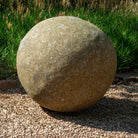 39" Large stone sphere on a gravel surface with grass in the background