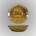 A hand-carved teak wood bowl with a smooth finish, showing natural wood grain, is displayed on a gray background