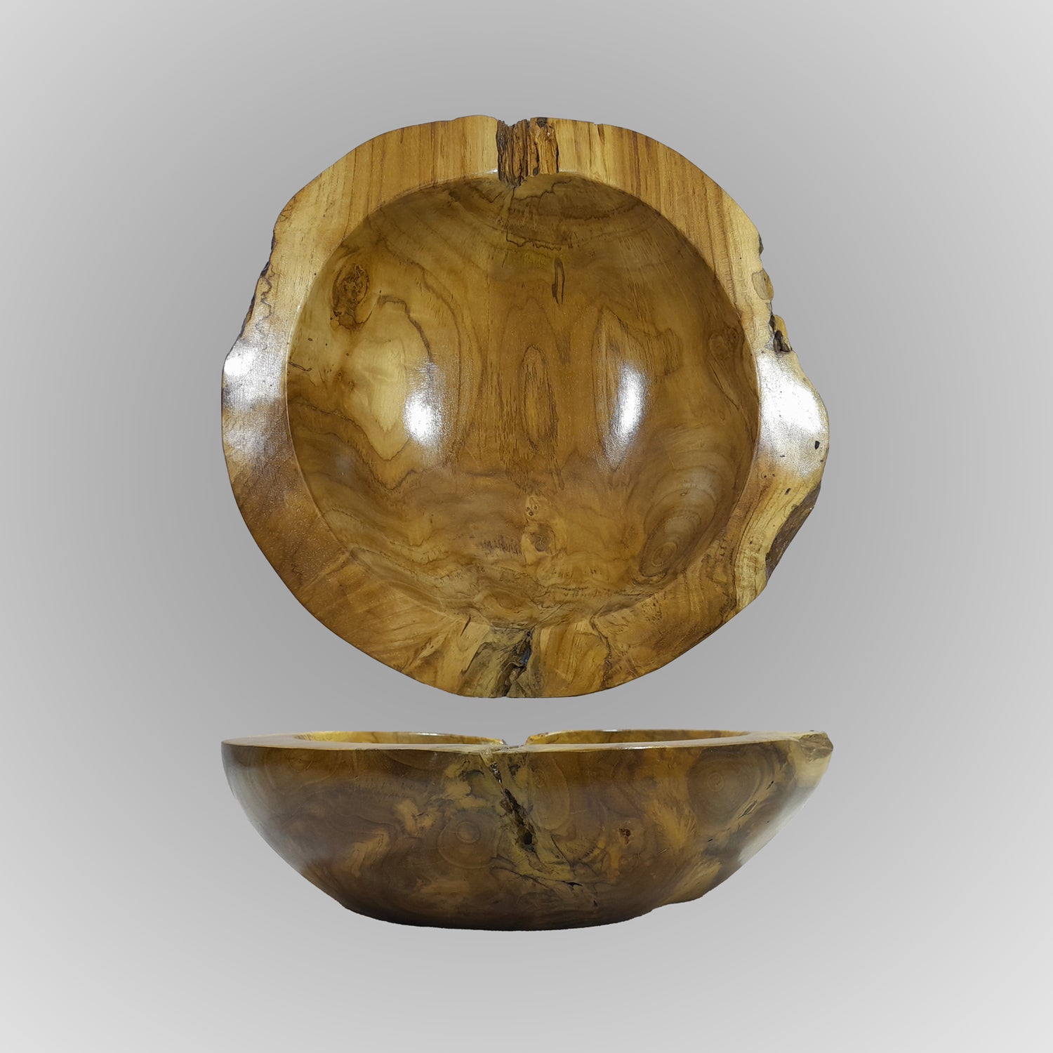 A hand-carved teak wood bowl with a smooth finish, showing natural wood grain, is displayed on a gray background