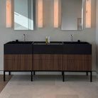 Bathroom vanity with black countertop and wooden cabinets, featuring two sinks.