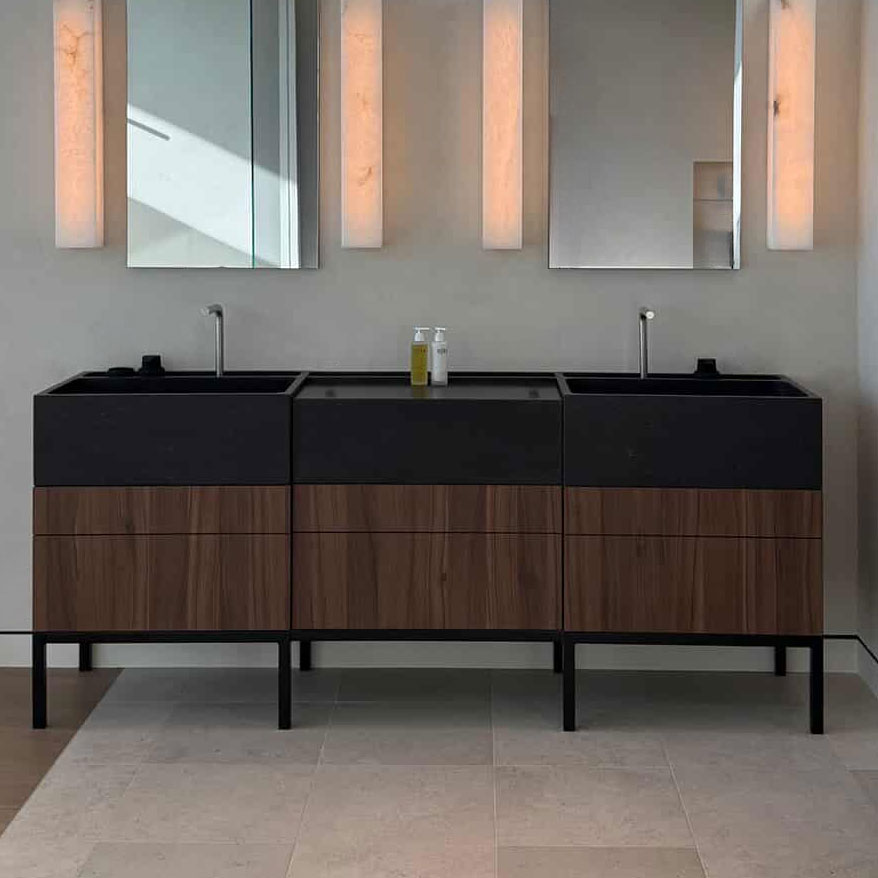 Bathroom vanity with black countertop and wooden cabinets, featuring two sinks.