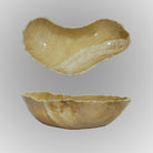 A free form onyx bowl with a smooth, curved shape against a gray background.