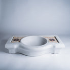 A white marble console sink with a mosaic inlay design on the top surface.