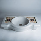 A white marble console sink with a mosaic inlay design on the top surface.
