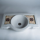 A white marble console sink with a mosaic inlay design on the top surface.