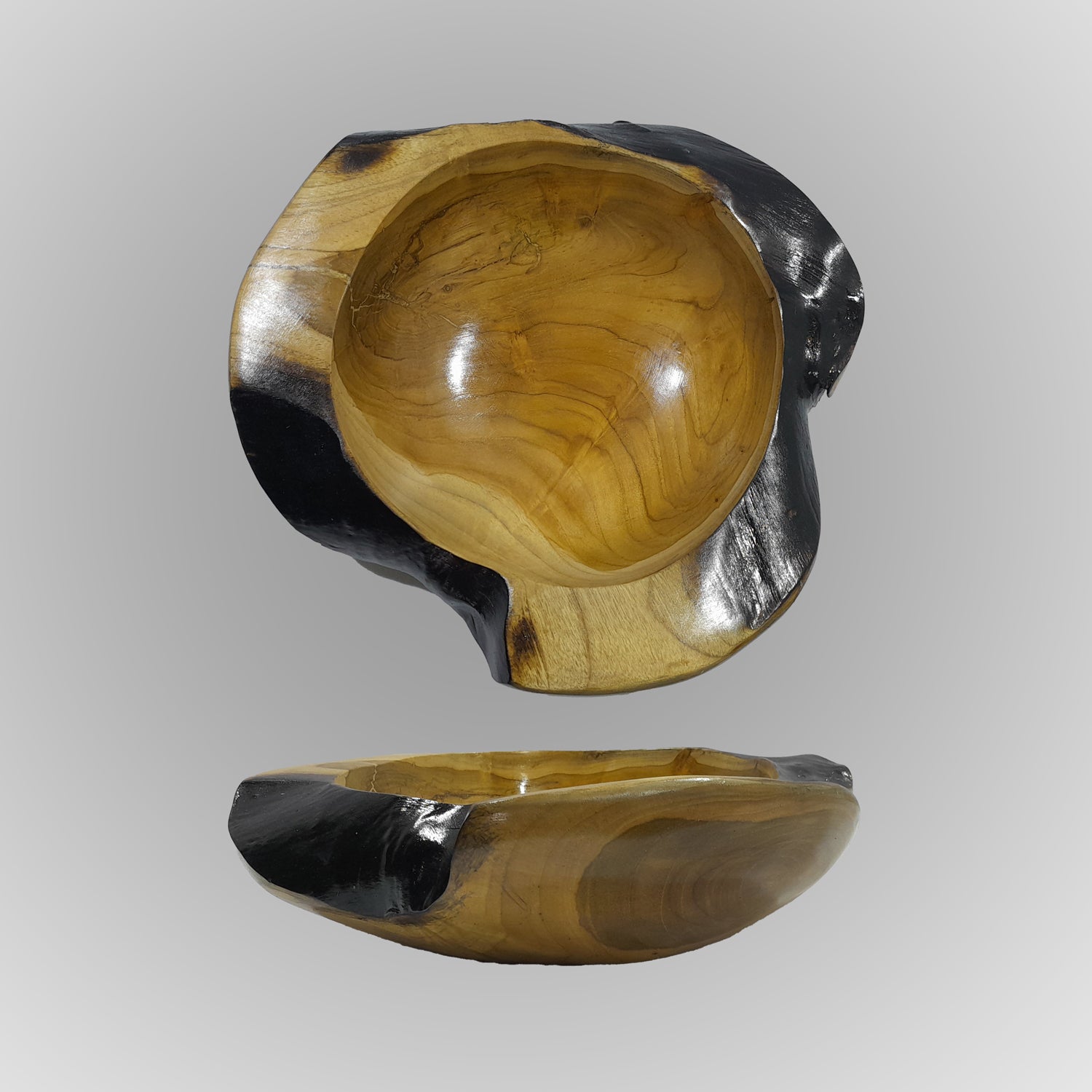 A hand-carved teak wood bowl with a smooth finish, showing natural wood grain, is displayed on a gray background