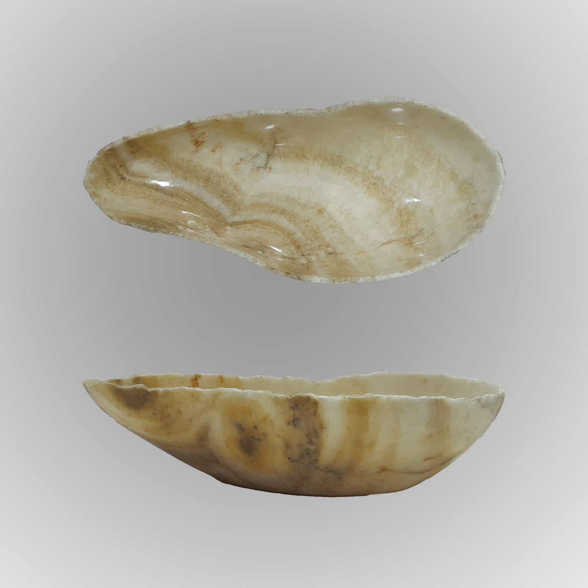 A free-form onyx bowl with a smooth, curved shape against a gray background. image 7 of 9