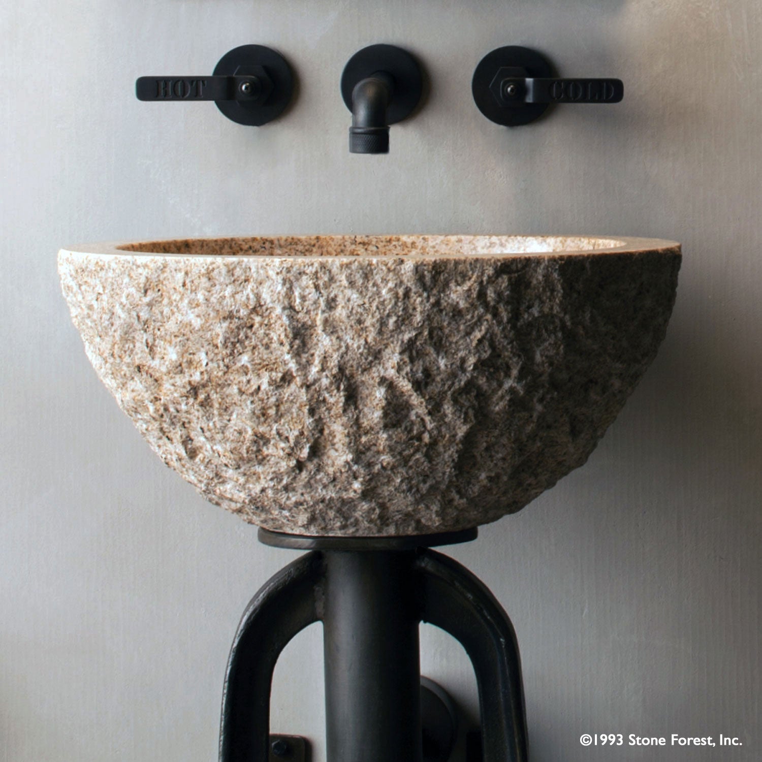 Oval Sink is carved from a block of beige granite with a rough chiseled exterior and polished interior.