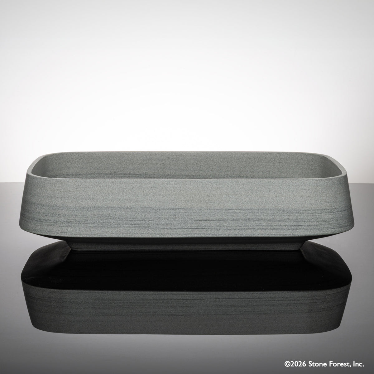 Rectangular gray vessel sink carved from grigio sandstone on a reflective surface with a light gray background image 2 of 4
