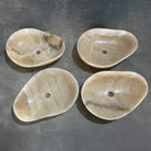 Four honey onyx stone sinks on a gray surface