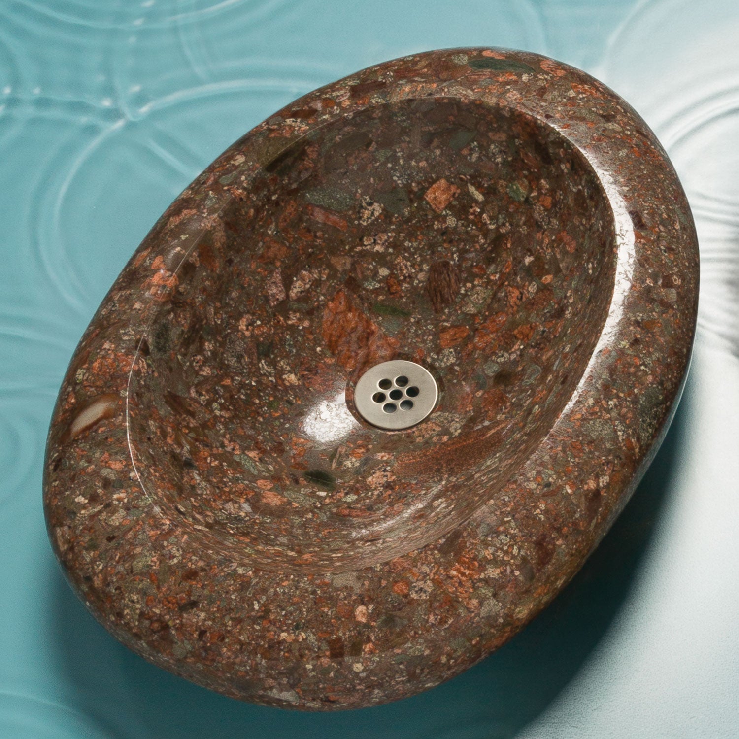 Brown stone sink with a silver drain on a blue background
