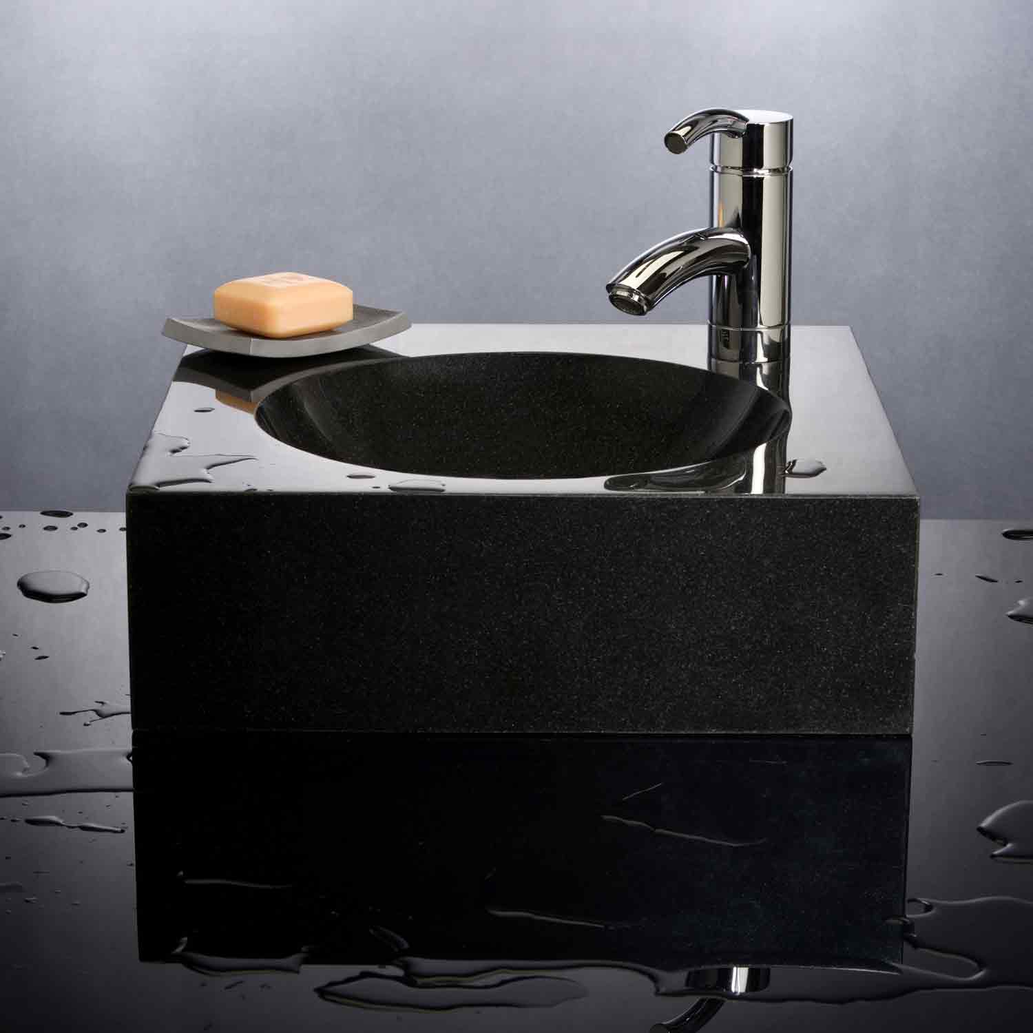A black granite vessel sink with an offset circular basin, mounted on a dark countertop