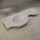 A white Carrara marble double renaissance sculpture on a textured surface.