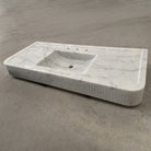 A white marble vanity with a fluted front, featuring an integral sink.