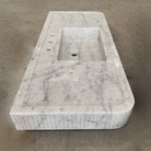 A white marble vanity with a fluted front, featuring an integral sink.
