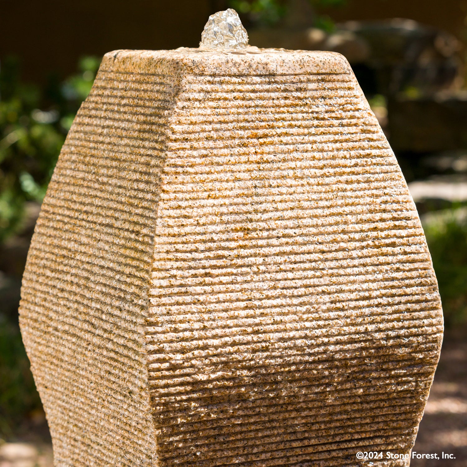 The Wave Fountain sculpted from a block of beige granite.
