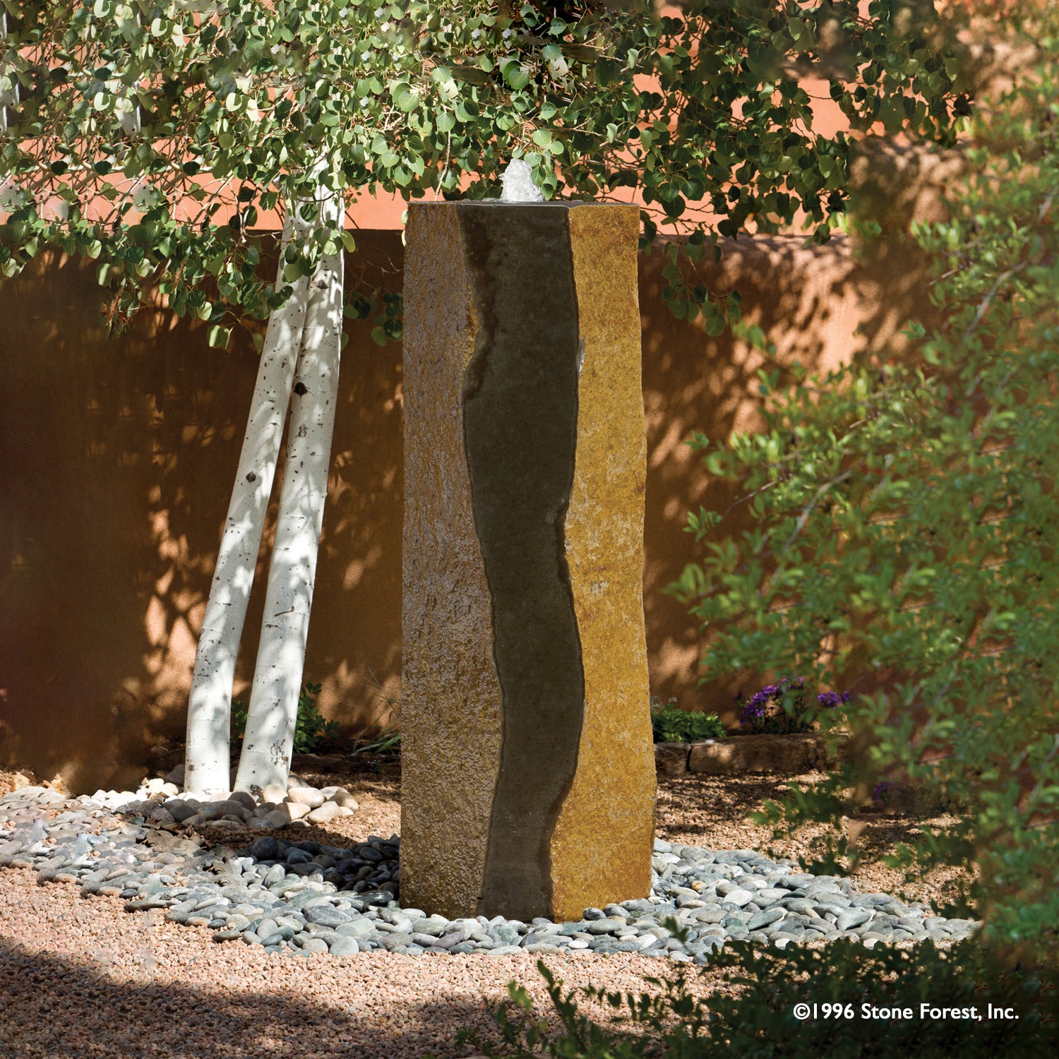 A large basalt column fountain with a polished black and gold stone surface, displayed outoors