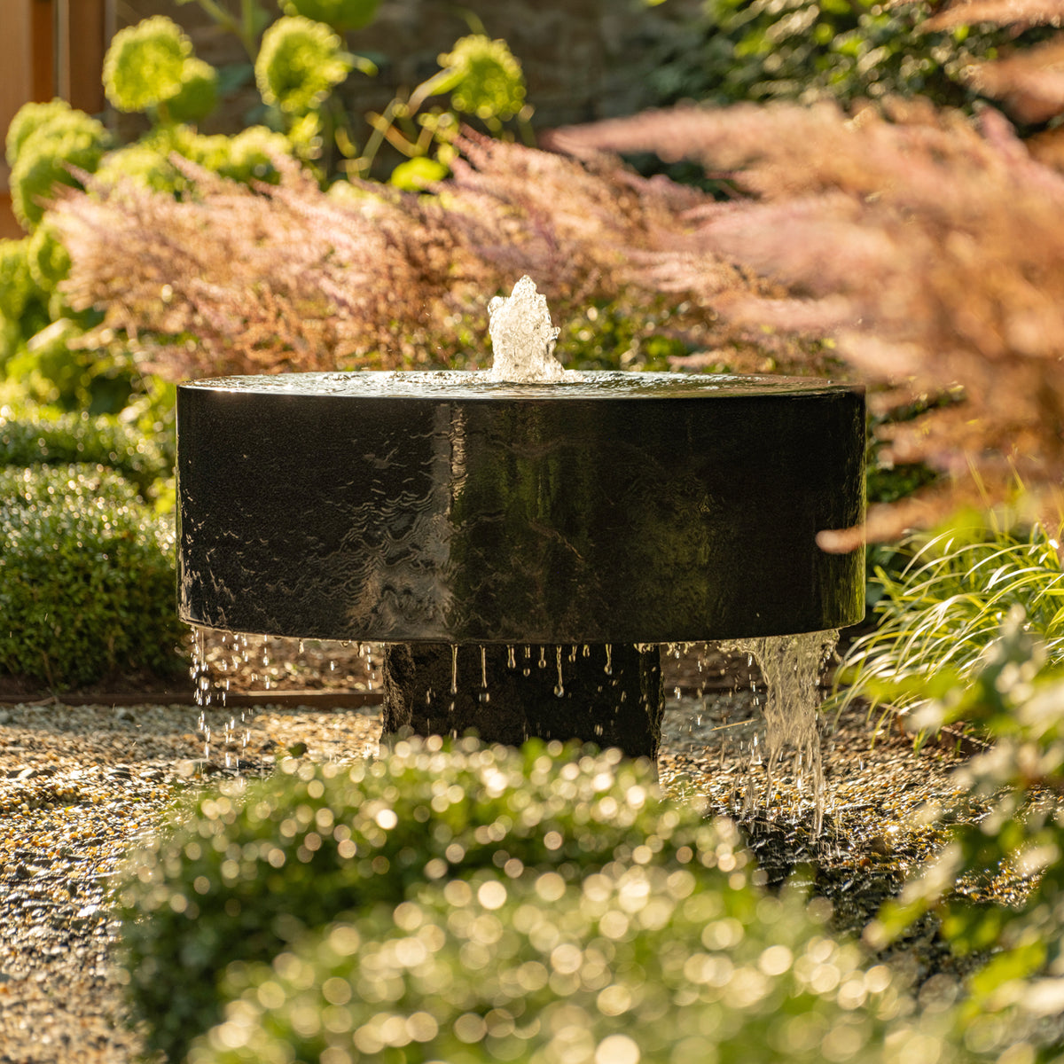Polished Millstone Fountain in black granite installed in a garden