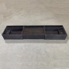 A three-piece black vanity sink made of basalt, placed on a concrete surface.