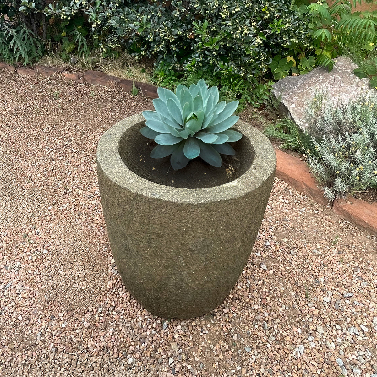 Cylindrical stone planter with a succulent plant on a gravel surface image 4 of 5