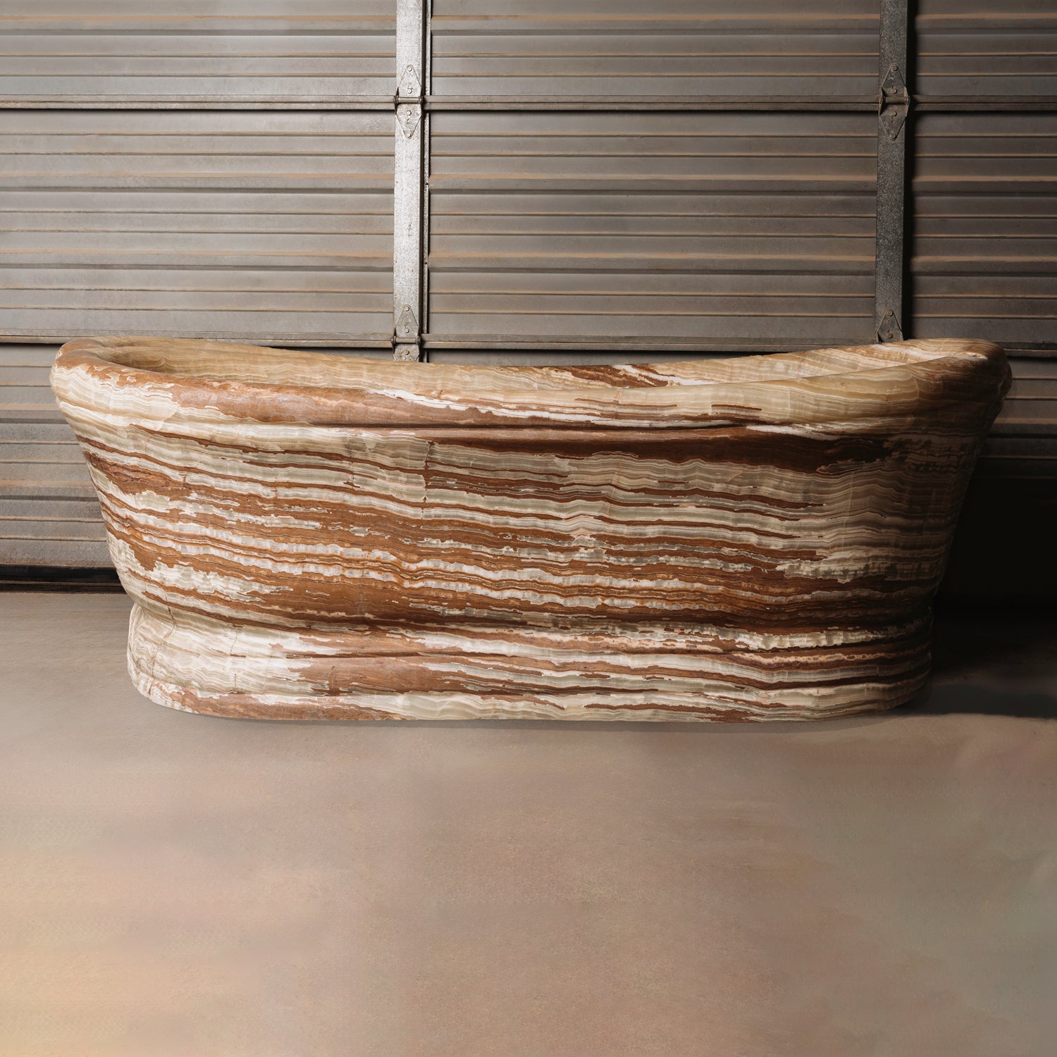 A large, oval-shaped, multi-color onyx planter placed on a concrete floor with wooden vertical elements in the background.