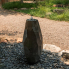 Lithic Fountain, a water feature in a garden setting with pebbles and plants.
