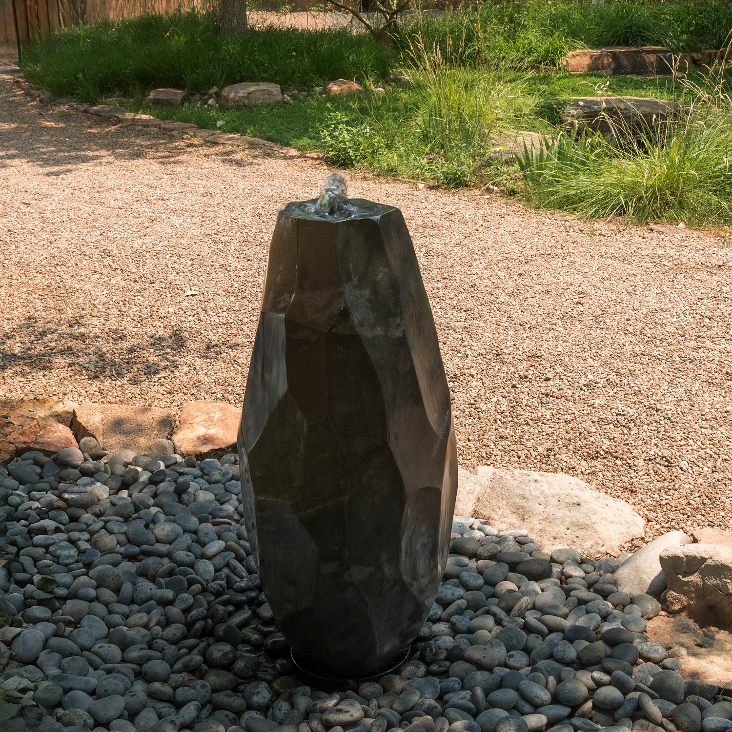 Lithic Fountain, a water feature in a garden setting with pebbles and plants.