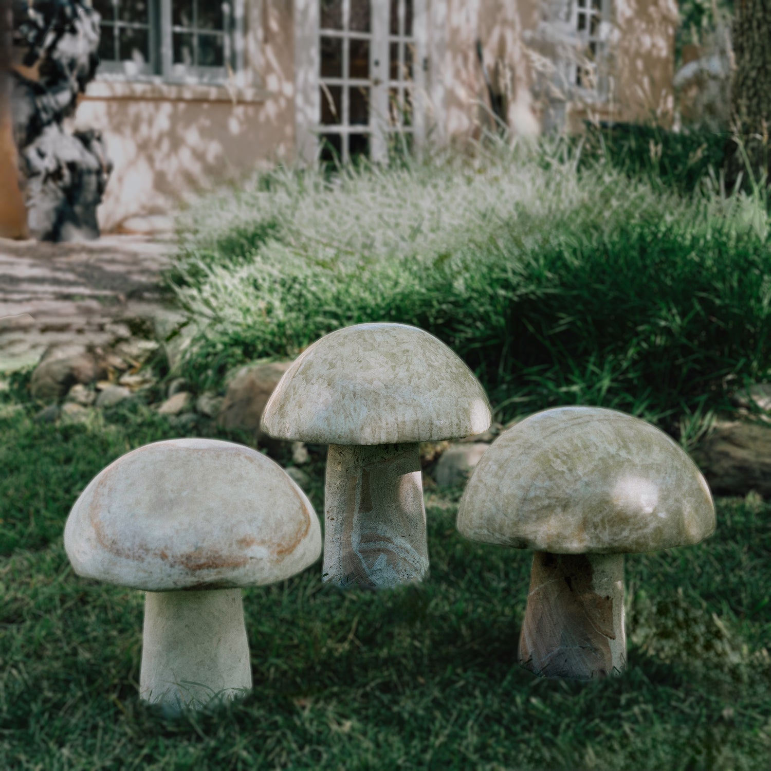 Three garden mushrooms carved from onyx, placed in a garden setting.
