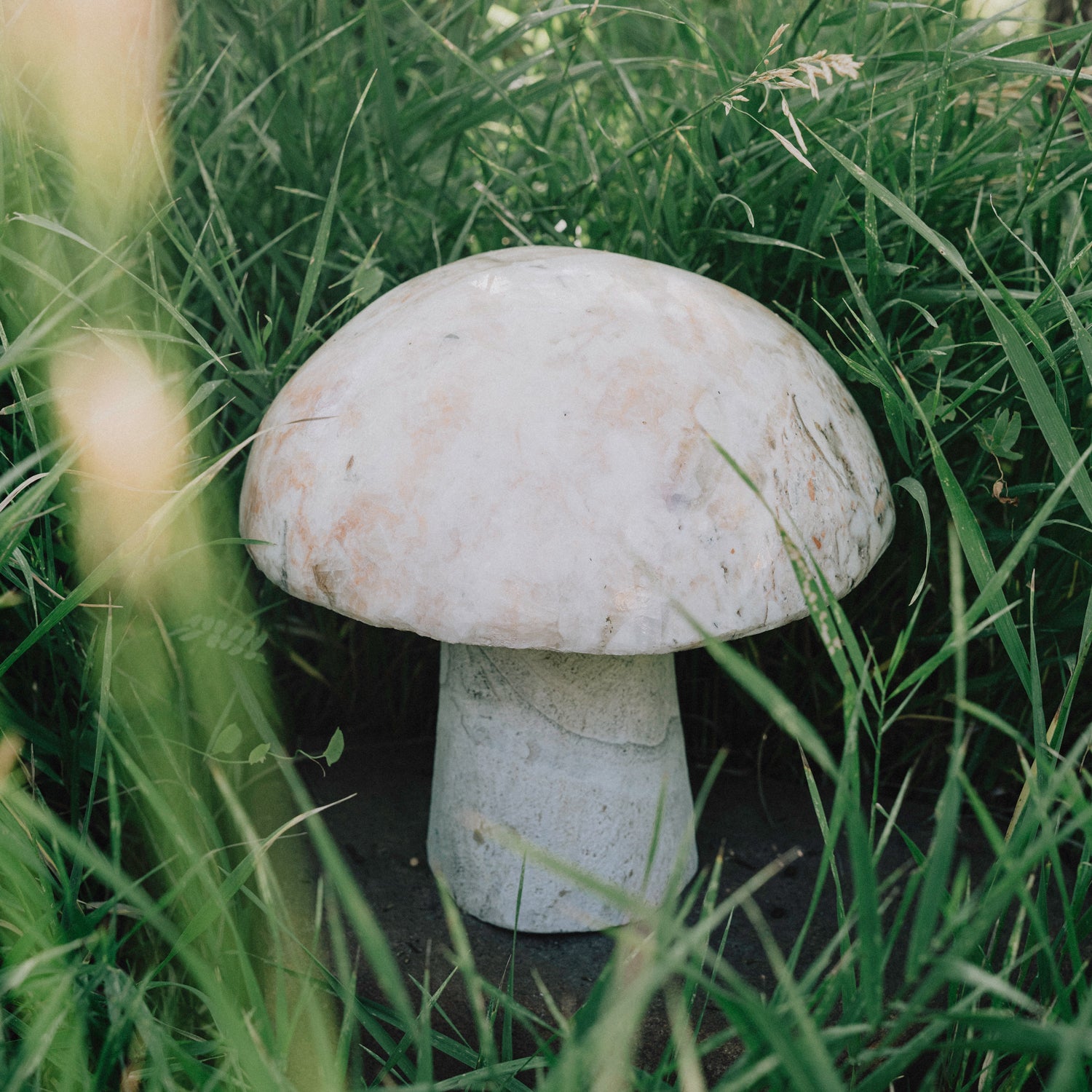 A garden mushroom carved from onyx, placed in a garden setting.
