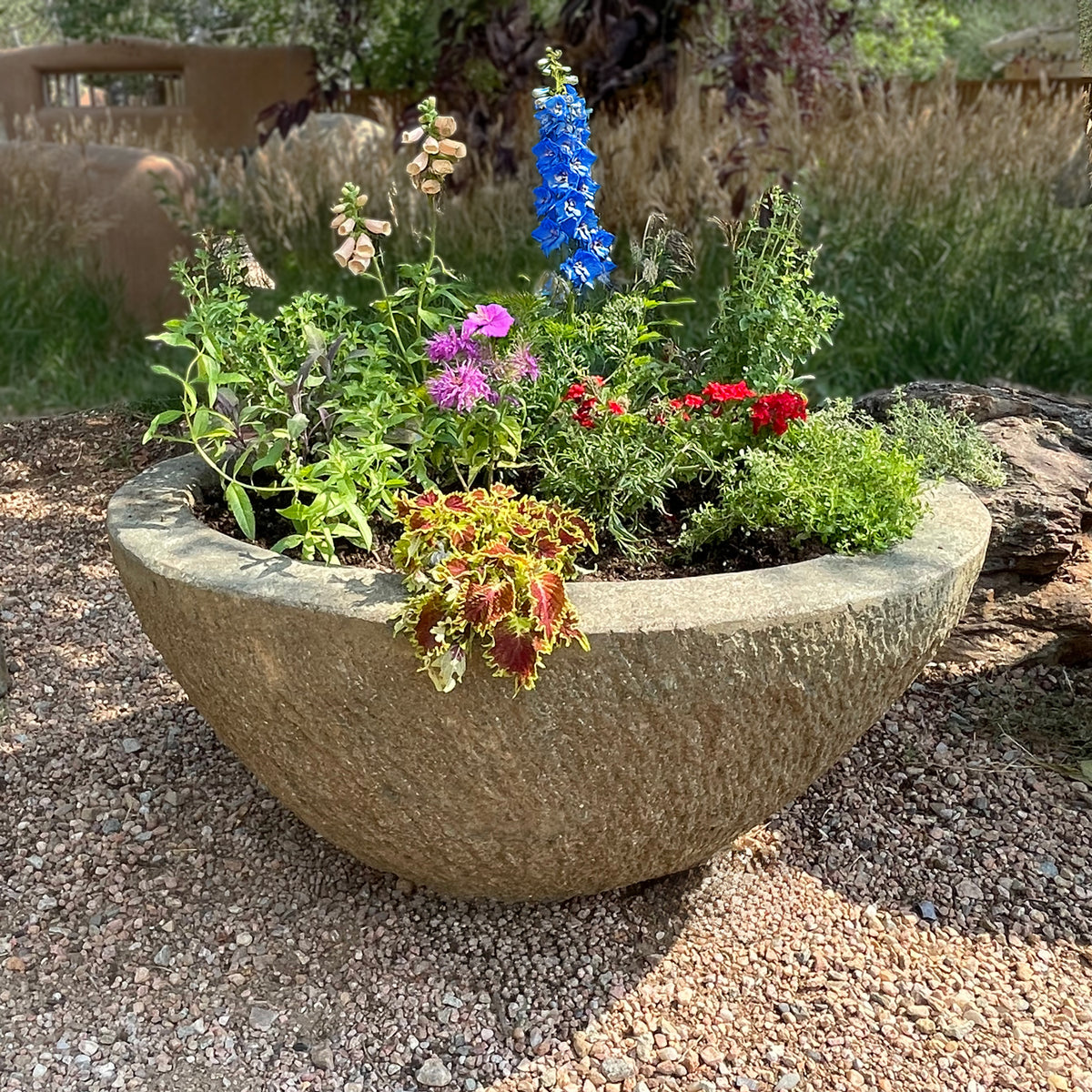 Decorative stone planter with colorful flowers in a garden setting image 2 of 5