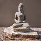 Stone Buddha statue on a rock with a plain background
