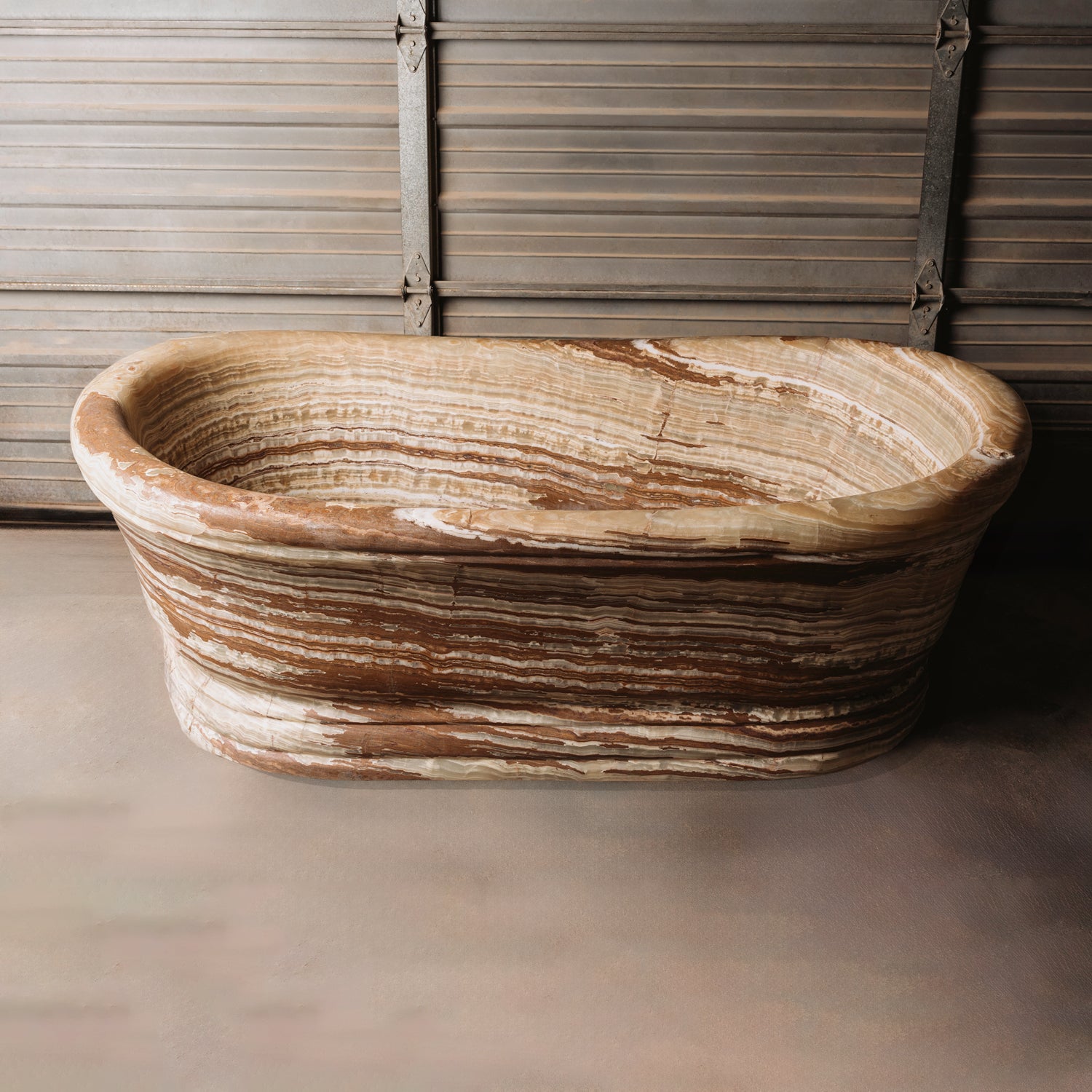 A large, oval-shaped, multi-color onyx planter placed on a concrete floor with wooden vertical elements in the background.