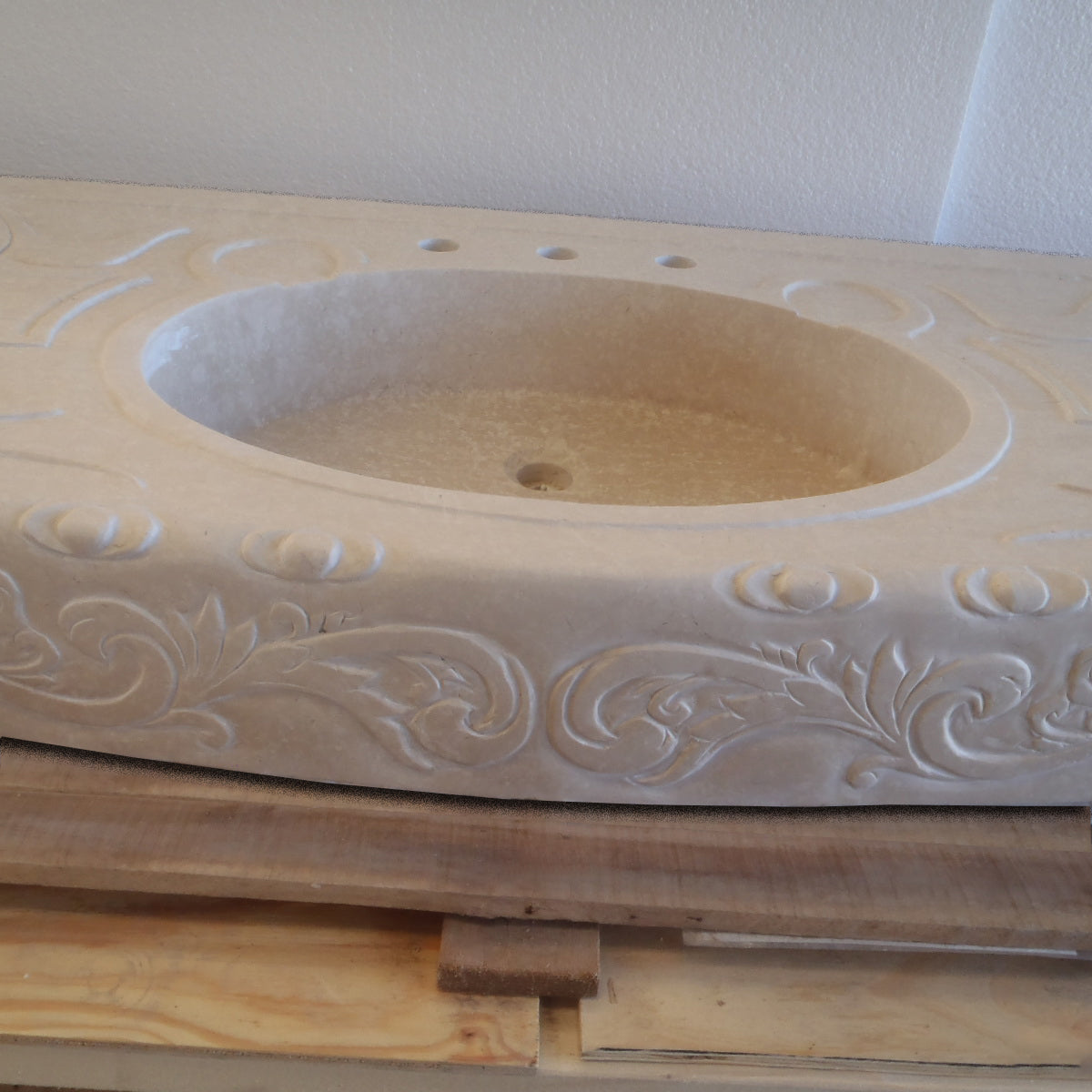 A beige marble vanity with carved details, close up of sink basin
