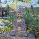 A hand-carved dark limestone Buddha statue with a painted finish, seated 